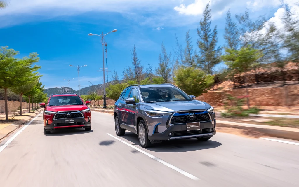 xe Corolla Cross 2024 màu đỏ và màu xanh xám chạy trên đường